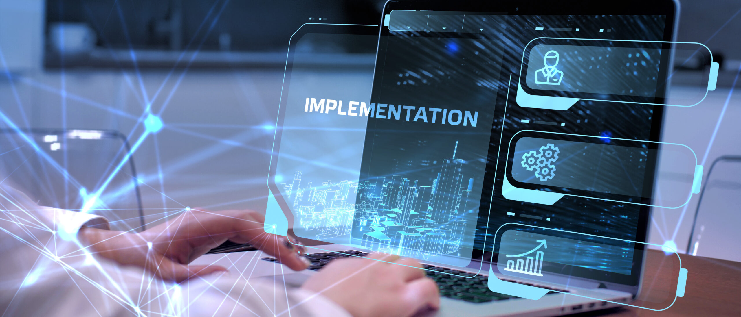 Eine Person tippt auf einem Laptop mit dem Wort "IMPLEMENTATION" und grafischen Elementen im Vordergrund.